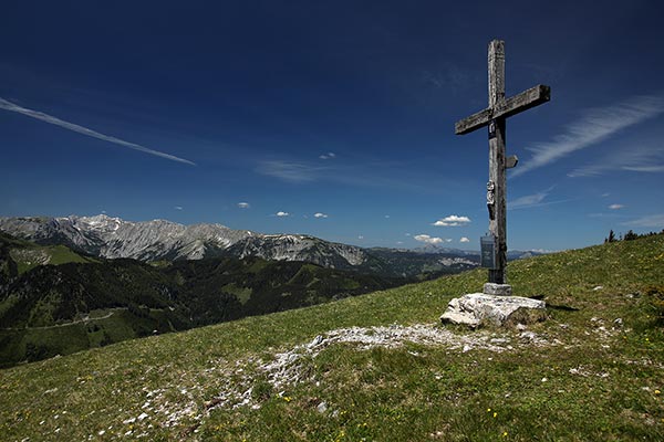 Blick auf ein Gipfelkreuz und im Hintergrund die Berge