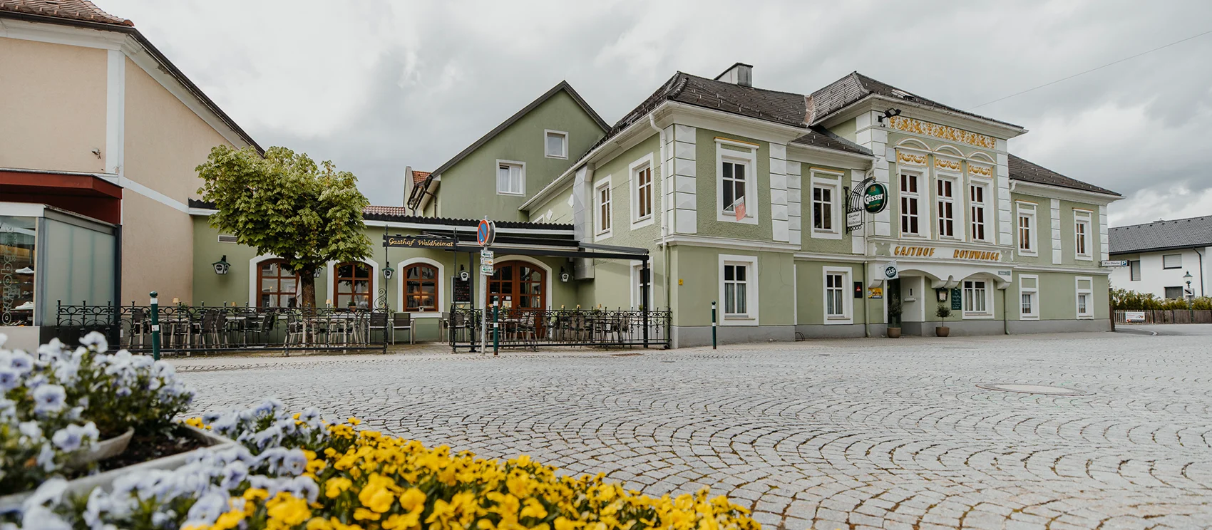 Außenansicht vom Gasthof - Blick auf das Schild Gasthof Waldheimat, dahinter die Fassade zu sehen.